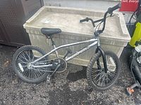 Side view of entire chrome-framed bike leaning against storage bin