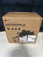 Photo of the original cardboard box packaging of the LifePro Mediripple Swing Machine showing front with product name and image of the device with power cord and control panel.