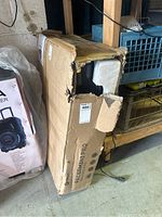 Damaged cardboard box of Lifepro Pacer Mini Pro Walking Pad with visible tear and corner damage.