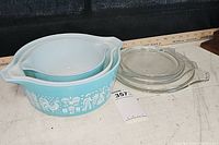 Top view of three bowls with lids, displaying wear and minor chip on lid surfaces.