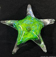 Top view of clear and green glass starfish paperweight showing vibrant swirled center and five arms
