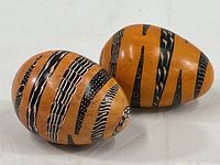 Two handmade soapstone eggs with painted snake patterns on a white surface