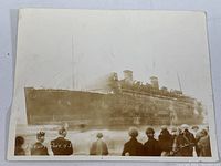 Photo showing side view of SS Morro Castle aground, crowd in foreground, some fading and discoloration on photo.