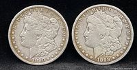 Obverse side of two Morgan Silver Dollar coins dated 1880 and 1898-S, showing Lady Liberty with detailed headgear.