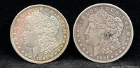 Front side of 1881-O and 1921-D Morgan Silver Dollars showing Lady Liberty profile with visible date and mint marks.