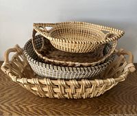 Stacked view of four handmade woven baskets showing various shapes and weaving patterns.