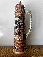 Full side view showing tall cylindrical stein with tower design and scenic knight on horseback reliefl