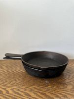 Two photos showing a vintage cast iron pan from side and top angles, highlighting the handle and pour spouts.