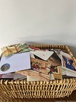 Wicker basket filled with assorted vintage postcards showing various colorful images including animals and artwork.