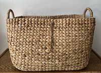 Front view of the large hand woven basket with two small handles on top edges