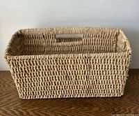 Front and side view of large rectangular wicker basket showing overall shape and texture.