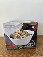Box showing a white porcelain bowl filled with a mixed salad rice dish, highlighting dishwasher, microwave, and oven safe features.