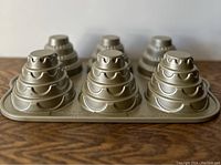Top-front view of vintage Nordicware cupcake pan showing six tiered cupcake molds in gold tone.