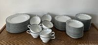 Full set of stacked plates and double-handled cups arranged on wooden surface