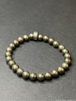Full view of pyrite beaded bracelet on dark background showing shape and bead texture.