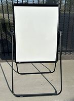 Front view of the whiteboard on a folding metal stand outdoors.