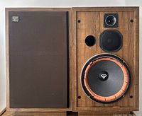 Pair of speaker cabinets side by side, left with grille installed, right with grille removed showing drivers