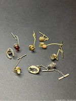 Photo showing eight vintage cufflinks with chain toggles on dark background, highlighting variety in design and metal finishes.