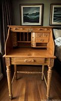 Full front view of the vintage quarter sawn oak roll top secretary desk showing interior compartments and drawers with carved wooden detailing.