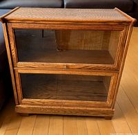 Front view of the oak wood lawyer's bookcase showing two glass-front compartments, top door closed, clear wood grain and rectangular base.