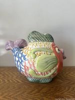 Side view of the colorful hand painted fish shaped pitcher showing detailed scales and fins.