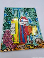 Front view of the ceramic wall hanging showing colorful wine bottles, grapes, glasses, and corks design.