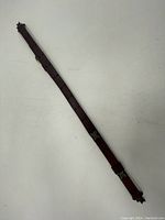 Dark brown leather sling laid flat on a white surface showing its full length and metal buckle adjustment points.