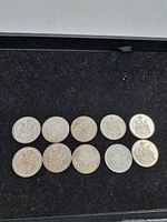 Top view of all ten Canadian 50 cent coins showing wear and tarnish on a black background.