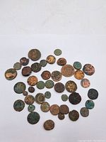 Top view of the assortment of approximately 40 Roman coins showing various sizes, colors, and corrosion levels.
