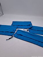 Four blue fabric Birks cutlery holders and polishing cloths laid flat showing their size and pockets for cutlery storage.