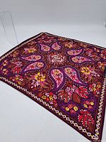 Full view of a printed silk handkerchief with maroon base featuring floral and paisley patterns in pink, purple, yellow and white colors.