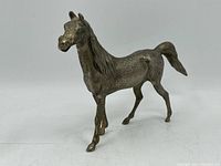 Front-side angle showing detailed horse figure with textured surface and patina.