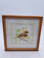 Full view of framed watercolour painting showing the small bird on a branch with foliage, titled and signed.