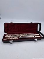 Full view of Yamaha silver flute in three pieces inside black hard case with red velvet interior.