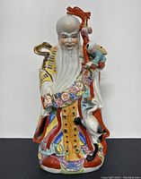 Front view of the colorful vintage Chinese porcelain statue showing detailed facial features, robes, child figure on staff, and crane.