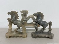 Front view of three soapstone figurines showing two horses on sides and a dragon in the middle.
