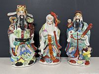 Front view of three hand-painted Chinese porcelain figurines showing detailed coloring and facial features