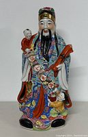 Front view of the porcelain statue showing detailed face, colorful robe, children figures, and scroll with Chinese characters.