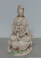 Front view showing porcelain Guanyin seated with child on lap, colorful floral details at base.