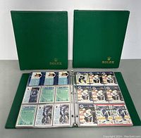Three green Rolex binders with hockey cards visible in one binder, showing cards arranged neatly in protective plastic pages.