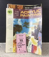 Front cover of The Art of Acrylic Painting instructional book showing colorful abstract painting cover with price sticker and auction lot tag