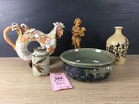 Front view of all four pottery pieces arranged in a row with the olive wood shepherd figurine behind them on a wooden surface.
