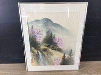Front view of framed Asian landscape painting showing mountain, waterfall, and house with pink blossoming trees.