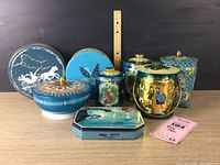 Eight vintage confectionery tins of varying shapes and styles arranged on a surface with a ruler for scale