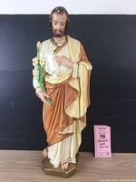 Front view of the large vintage chalkware Jesus statue, showing detailed hand-painting and floral element held in left hand with a pink Maxsold label on the base.