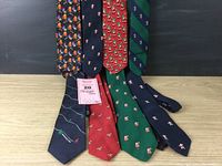 Eight Christmas-themed ties arranged with tags visible on two. Close-up of festive patterns including penguins, candy canes, stripes.