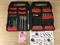 Full set in black plastic case showing various screwdriver bits, drill bits, spade bits and accessories, with instruction sheet visible, all neatly organized and lightly used.