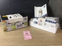 Photo showing Geedel rotating drum grater boxed with manual and Zakarian Safe Slice Mandoline in packing material and instructions.