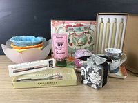 Wide shot showing assortment including floral bowls, Fragonard candle tin, LED candles, mugs, and decorative boxes