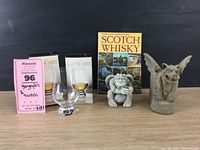 Two Levenger gargoyle pen holders, two Glencairn whiskey glasses in boxes, and Scotch whiskey book displayed on a table.